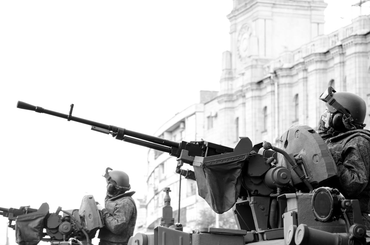 about-us Monochrome image of soldiers in armored tanks, equipped with rifles, patrolling urban surroundings.